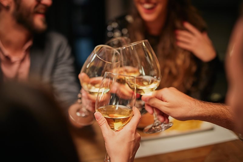 Kollegaer fester og skåler i dejlig hvidvin til personalefest med sjove indslag.